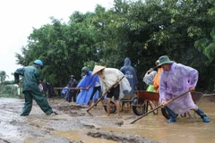 Các chiến sỹ bộ đội giúp khắc phục sự cố sạt lở đường để các phương tiện qua lại. (Ảnh: Dương Giang/TTXVN)