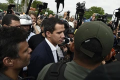 Thủ lĩnh đối lập Juan Guaido (giữa) kêu gọi nhóm binh sỹ được trang bị vũ khí "nổi dậy" nhằm lật đổ Tổng thống Nicolas Maduro. (Ảnh: AFP/TTXVN)