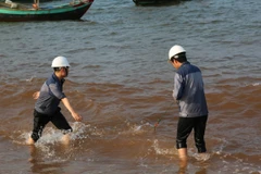 Cán bộ môi trường đang lấy mẫu nước để kiểm tra. (Ảnh: Mạnh Thành/Vietnam+)