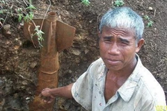 Ông Ma H Tấc và quả bom vừa được phát hiện. (Nguồn: nhandan.org.vn)