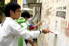 Thanh niên tình nguyện phường Liễu Gia, quận Ba Đình xóa bỏ quảng cáo rao vặt. (Ảnh: Đình Trân/TTXVN) 