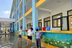 Giáo viên, nhân viên Trường Trung học Cơ sở Nam Phương Tiến A dọn vệ sinh trường lớp sau nhiều ngày bị ngập sâu, hôm 28/9 vừa qua. (Ảnh: Nguyễn Cúc/TTXVN)