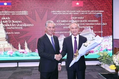 Phó Chủ tịch UBND Thành phố, Chủ tịch Hội hữu nghị Việt Nam-Lào Thành phố Hồ Chí Minh Ngô Minh Châu (trái) tặng hoa chúc mừng Tổng lãnh sự Lào tại Thành phố Hồ Chí Minh Phonesy Bounmixay (phải). (Ảnh: Xuân Khu/TTXVN)