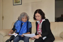 Bà Trần Tố Nga (trái) và phóng viên TTXVN cùng xem tập hồ sơ tập hợp 20.000 chữ ký của người dân tỉnh Sóc Trăng ủng hộ vụ kiện da cam. (Ảnh: Bích Hà/Vietnam+)