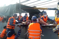 Sau khi sơ cứu, lực lượng cán bộ, chiến sỹ Làng chài đã chuyển ngư dân bị nạn lên tàu Hải quân 788 để đưa sang đảo Phan Vinh tiếp tục chữa trị. (Ảnh: TTXVN phát)