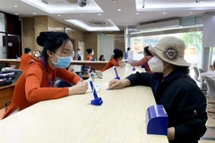 Khách hàng giao dịch tại ngân hàng Sacombank. (Ảnh: TTXVN phát)