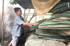 Anh Âu Văn Khải, ngụ tại ấp Tắc Trúc, xã Nhơn Hội, huyện An Phú, tỉnh An Giang, xếp gọn 2.000m lưới đánh cá để chờ bán vào mùa lũ năm sau. (Ảnh: Hồng Nhung/TTXVN)