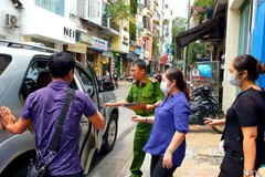 Cơ quan chức năng dẫn giải những người liên quan đi sau khi thực hiện việc khám xét Công ty PIT Travel. (Ảnh: TTXVN phát)