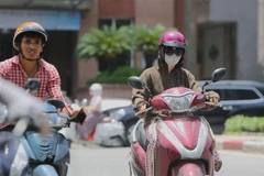 Người dân ra đường với trang phục kín mít để tránh cái nắng gay gắt. (Ảnh: Thành Đạt/TTXVN)