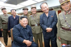 Nhà lãnh đạo Triều Tiên Kim Jong-un (trái, phía trước) theo dõi vụ thử nghiệm vũ khí chiến thuật mới tại một địa điểm không xác định. (Ảnh: AFP/TTXVN)