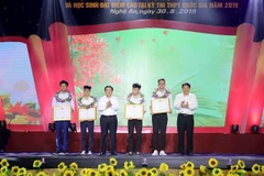 Ông Nguyễn Xuân Thắng, Chủ tịch Hội đồng lý luận Trung ương, Giám đốc Học viện Chính trí quốc gia Hồ Chí Minh, và ông Nguyễn Đắc Vinh, Bí thư Tỉnh ủy Nghệ An tặng Bằng khen cho bốn học sinh đạt thành tích cao trong các kỳ thi Quốc tế và khu vực. (Ảnh: Bíc