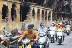 Người dân sinh sống tại đây phải đeo khẩu trang mỗi khi đi qua khu vực cháy nhà máy Bóng đèn Phích nước Rạng Đông. (Ảnh: Thành Đạt/TTXVN)