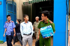 Cơ quan chức năng dẫn giải những người liên quan đi sau khi thực hiện việc khám xét Công ty PIT Travel. (Ảnh: TTXVN phát)