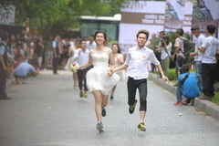 Các cặp đôi vẫn diện những bộ lễ phục đám cưới rất đẹp nhưng thay vì đi giày da và guốc, họ sắm cho mình những đôi giày chạy bộ. (Ảnh: Minh Sơn/Vietnam+)