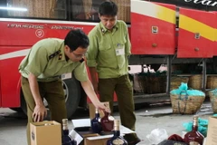 Lực lượng chức năng đang kiểm tra số rượu vừa được thu giữ. (Ảnh: Hải Yến/TTXVN)