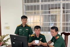 Thiếu tá Thiều Hữu Cường (ngồi giữa) với thiết bị IoT cảnh báo nguy cơ đột quỵ. (Ảnh: TTXVN phát)