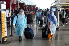 Hành khách đeo khẩu trang và mặc quần áo bảo hộ phòng lây nhiễm COVID-19 tại sân bay quốc tế Indira Gandhi ở New Delhi, Ấn Độ. (Ảnh: THX/TTXVN)