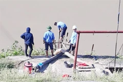 Lực lượng chức năng lắp đặt trạm bơm dã chiến để lấy nước sản xuất tại huyện Đô Lương. (Ảnh: TTXVN phát)