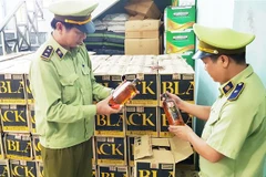 Lực lượng chức năng kiểm tra số rượu ngoại lậu vừa bắt giữ. (Ảnh: Võ Dung/TTXVN)