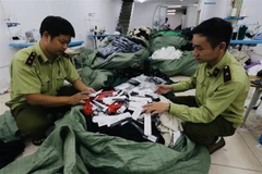 Lực lượng chức năng kiểm tra số hàng may mặc nhập khẩu được thay thế bằng nhãn mác IFU. (Ảnh: Trần Việt/TTXVN)