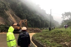 Lực lượng chức năng xử lý hiện trường sạt lở cho các phương tiện qua lại. (Ảnh: Quang Thái/TTXVN)