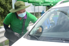 Nhân viên một nhà cung cấp dịch vụ thu phí không dừng dán thẻ định danh cho phương tiện. (Ảnh: Việt Hùng/Vietnam+)