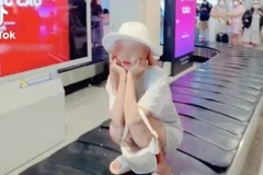 Một cô gái leo lên băng chuyền hành lý ngồi xổm để quay clip đăng TikTok.