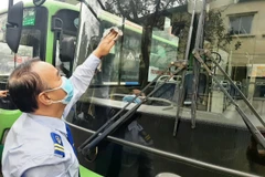 Anh Hồ Xuân Phong, lái xe tuyến số 33 thuộc Xí Nghiệp Tân Đạt đang vệ sinh xe sau hành trình đón khách. (Ảnh: Việt Hùng/Vietnam+)