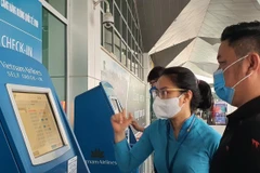 Nhân viên Vietnam Airlines hướng dẫn giúp hành khách làm thủ tục trực tuyến tại Kios check-in online ở một sân bay. (Ảnh: CTV/Vietnam+)