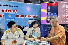 Người dân tham gia trải nghiệm các dịch vụ thanh toán không tiền mặt tại gian hàng của Cục Thuế TP. Hồ Chí Minh. (Ảnh: Hứa Chung/TTXVN)