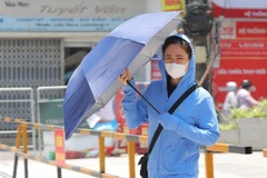 Một người dân trang bị nhiều đồ chống nắng, nóng khi phải di chuyển ngoài trời. (Ảnh: Hoàng Hiếu/TTXVN)