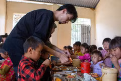 Ca sỹ Đen Vâu cẩn thận bóc tôm cho học sinh vùng cao trong bữa ăn bán trú. (Ảnh: PV/Vietnam+)