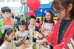 Các em học sinh và phụ huynh chăm chú theo dõi cách pha trà. (Ảnh: Phạm Mai/Vietnam+)