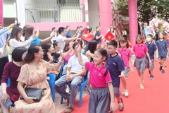 Những học sinh mới của Trường TH School bước vào trong tiếng chuông chào đón của các học sinh cũ và sự cổ vũ nồng nhiệt của các phụ huynh. (Ảnh: PM/Vietnam+)