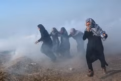 Người biểu tình Palestine chạy trốn khỏi khu vực hơi cay trong cuộc xung đột với binh lính Israel tại biên giới Gaza-Israel ngày 15/5. (Nguồn: EPA/TTXVN)