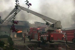 Xe thang chuyên dụng được điều đến phun nước khống chế đám cháy. (Nguồn: TTXVN phát)