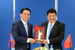 Ông Vilayvong Bouddakham (trái) tặng quà lưu niệm cho ông Huỳnh Cách Mạng. (Ảnh: Xuân Khu/TTXVN)