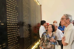 Các nguyên lãnh đạo TTXVN qua các thời kỳ và các đại biểu thân nhân gia đình thương binh-liệt sỹ xem Văn bia ghi danh sách các liệt sỹ của TTXVN. (Ảnh: Quý Trung/TTXVN)