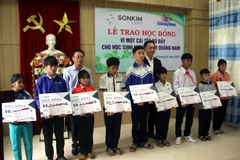 Ông Lê Văn Nhi, Tổng Biên tập Báo Quảng Nam cùng lãnh đạo Công ty SonKim Land trao học bổng cho các em học sinh. (Ảnh: Trịnh Bang Nhiệm/TTXVN)
