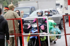 Người dân mang nhu yếu phẩm đến chốt kiểm dịch để cung cấp cho người thân trong vùng phong tỏa. (Ảnh: Văn Đức/TTXVN)