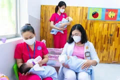 Bảo mẫu và bác sỹ Bệnh viện Hùng Vương cùng chăm sóc trẻ sơ sinh có mẹ mắc COVID-19 chờ người thân đón về. (Ảnh: TTXVN phát) 