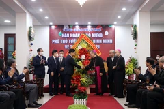 Ủy viên Bộ Chính trị, Phó Thủ tướng Thường trực Chính phủ Phạm Bình Minh tặng hoa chúc mừng Lễ Giáng sinh tại Tòa giám mục Huế. (Ảnh: Đỗ Trưởng/TTXVN)