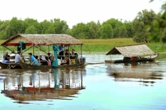 Du khách tham quan Vườn quốc gia Tràm Chim bằng nhà nổi trên sông. (Ảnh: An Hiếu/TTXVN)