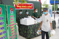 Người dân xã Phước Đồng, thành phố Nha Trang, tỉnh Khánh Hòa nhận hỗ trợ gạo và nhu yếu phẩm từ gian hàng 0 đồng do Bộ Chỉ huy Quân sự tỉnh Khánh Hòa tổ chức. (Nguồn: TTXVN) 