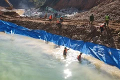 Lực lượng chức năng nắn dòng chảy mới để phục vụ công tác tìm kiếm dưới lòng suối Rào Trăng. (Ảnh: TTXVN phát)