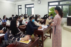 Giáo viên trường Trung học phổ thông Hoàng Hoa Thám hướng dẫn học sinh đảm bảo an toàn phòng dịch. (Ảnh: Văn Dũng/TTXVN) 