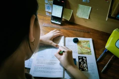 Em Cẩm Ly, học sinh lớp 7 trường THCS Lê Bình (quận Cái Răng, thành phố Cần Thơ) ghi chép lại bài trong thời gian lên lớp trực tuyến. (Ảnh: Thanh Liêm/TTXVN)
