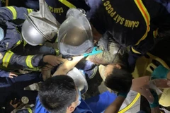 Lực lượng cảnh sát Phòng cháy chữa cháy phối hợp đưa nạn nhân mắc kẹt trong vụ sập giàn giáo ra ngoài an toàn. (Nguồn: baogiaothong)