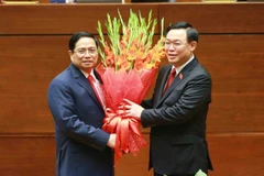 Chủ tịch Quốc hội Vương Đình Huệ tặng hoa chúc mừng Thủ tướng Phạm Minh Chính. (Ảnh: Phương Hoa/TTXVN)