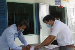 Cán bộ Lao động, Thương binh và Xã hội xã Bình Quới, huyện Châu Thành đến từng nhà trao tiền hỗ trợ cho lao động tự do tạm nghỉ việc do dịch COVID-19. (Ảnh: Đức Hạnh/TTXVN)